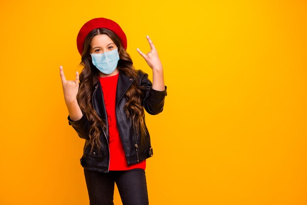 Portret van een cool langharig meisje dat een veiligheidsmasker draagt, stop cov influenza show horn sign
