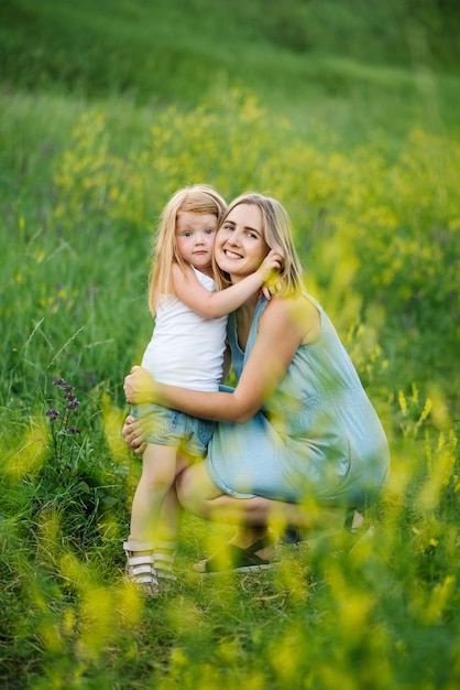 Foto portret van een dochter knuffelen moeder op de natuur op zomerdag vakantie moeder en meisje lopen in het park gelukkige jonge familie tijd samen doorbrengen concept van vriendelijke familie close-up