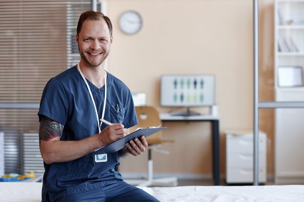 Portret van een dokter in uniform die naar de camera glimlacht terwijl hij een document in zijn kantoor invult