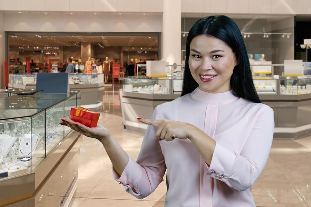 Portret van een donkerbruine Aziatische vrouw die een rode giftdoos adverteert