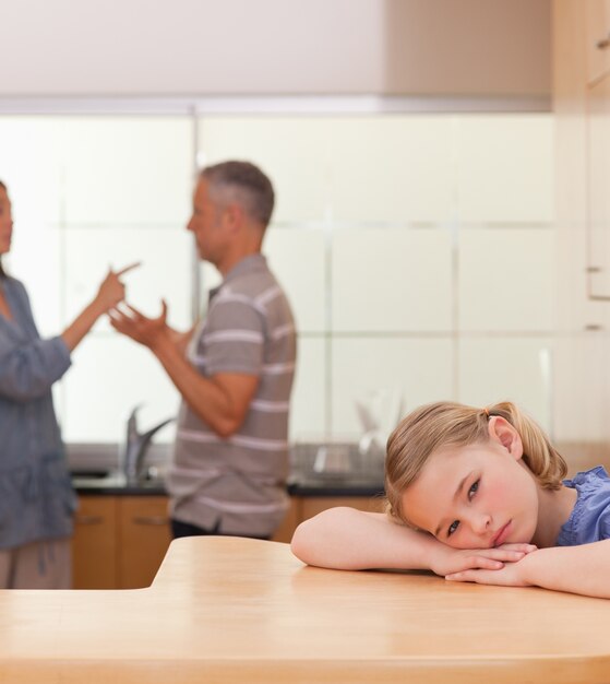 Portret van een droevig meisje dat haar ouders het ruzie luisteren luistert