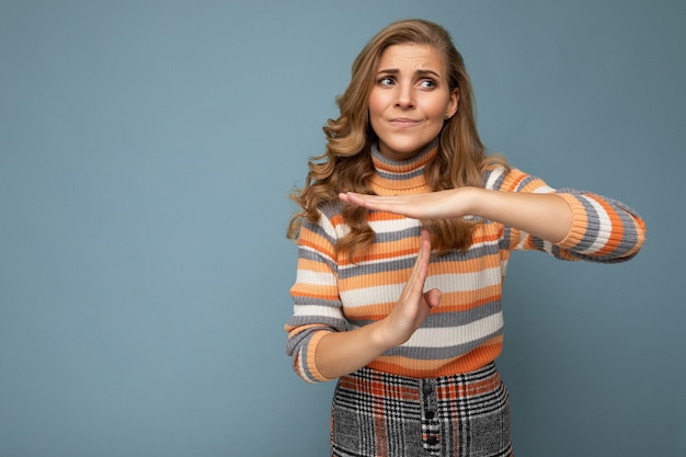 Portret van een droevige jonge, mooie blonde krullende vrouw met oprechte emoties die een stijlvolle gestreepte trui draagt