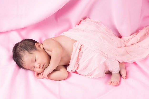 Portret van een één maand oud slapend, pasgeboren babymeisje op een roze deken. Concept portret studio mode pasgeboren.