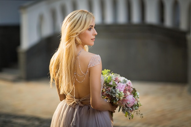 Portret van een elegante mooie vrouw die grijze trouwjurk draagt en poseert