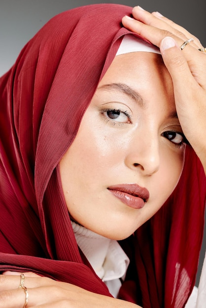 Portret van een elegante moslimvrouw in een hijab die zich voordeed in een studio Headshot van een stijlvol stijlvol zelfverzekerd Arabisch model dat tegen een grijze achtergrond staat Modieuze vrouw die een hoofddoek draagt