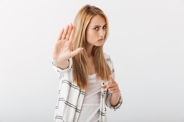 Portret van een ernstige jonge toevallige vrouw die stop toont