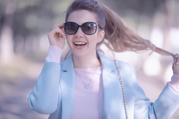 portret van een europees mooi vrouwelijk model met een zonnebril / meisje dat buiten loopt, gelukkig vrolijk meisje met een bril