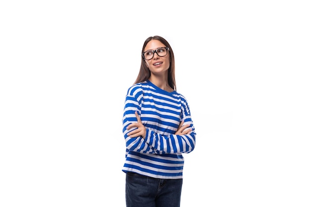 Portret van een Europese mooie brunette jonge dame in een casual gestreepte trui en jeans op een witte