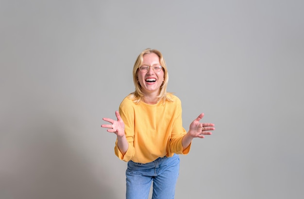 Portret van een extatische zakenvrouw met een bril die naar de camera gebaar maakt en lacht op een witte achtergrond