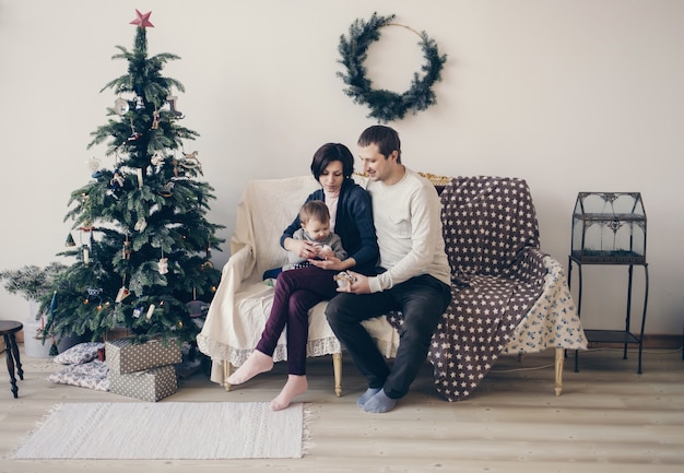 Portret van een familie zittend op een bank naast de kerstboom