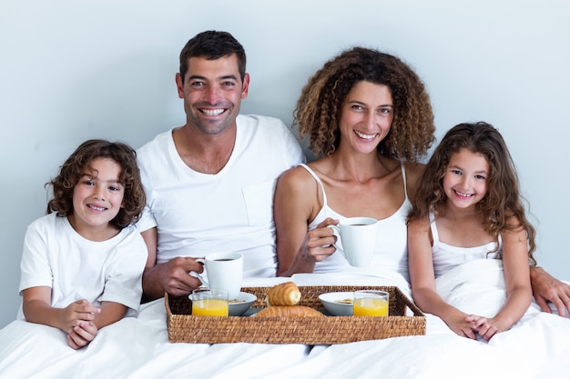 Portret van een familiezitting met ontbijtdienblad in bed