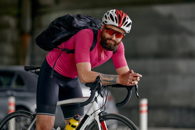Portret van een fietser die onder een brug staat met een fiets die voor de camera poseert tegen een