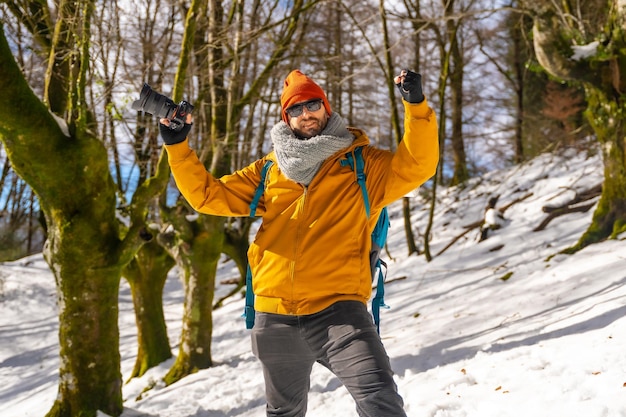 Portret van een fotograaf die trekt met een rugzak die foto's maakt in een beukenbos met sneeuwpret en winterhobby's