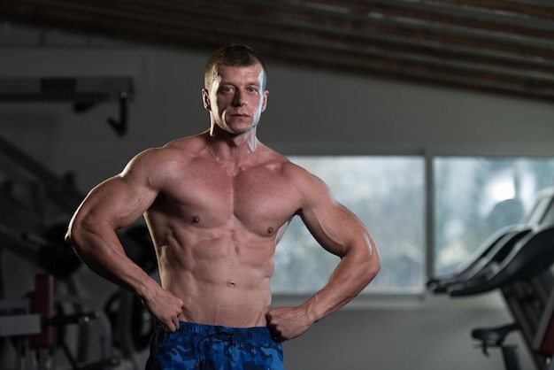 Portret van een fysiek fitte man die zijn goed getrainde lichaam laat zien Gespierde atletische bodybuilder Fitness Model poseren na oefeningen