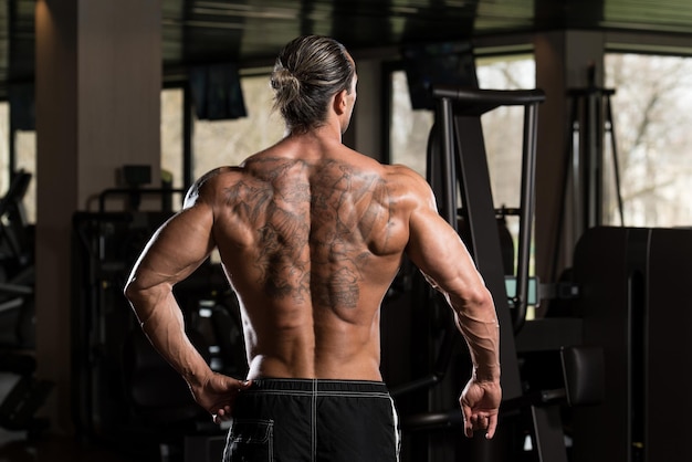 Portret van een fysiek fitte man in een modern fitnesscentrum die poses op zijn rug laat zien