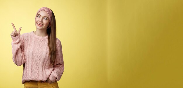 Portret van een geamuseerd, geïnteresseerd, schattig Europees meisje met een sweater-hoofdband die linksboven kijkt