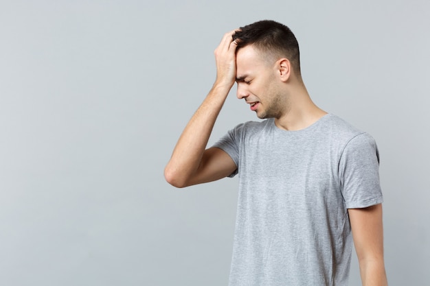 Portret van een gefrustreerde huilende jongeman in vrijetijdskleding die zijn ogen gesloten houdt en zijn hand op zijn hoofd legt