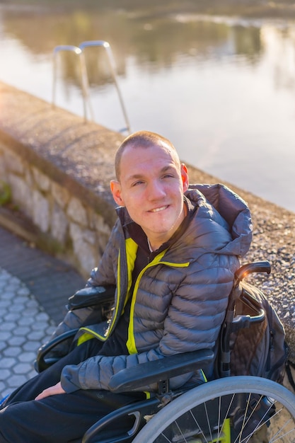 Foto portret van een gehandicapte persoon in een rolstoel bij een rivier in de stad zonsondergang