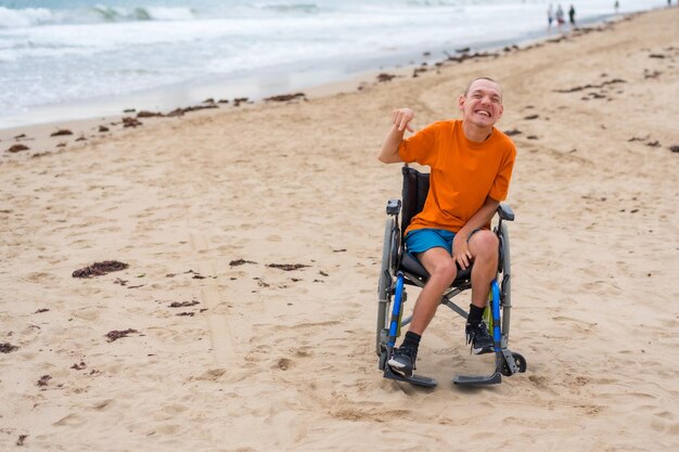 Portret van een gehandicapte persoon in een rolstoel op het strand die in de zomer plezier heeft