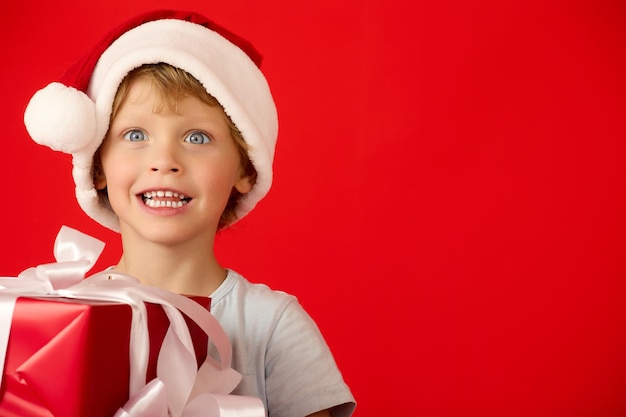 Portret van een geïrriteerde kleine blanke jongen met een grappige hoed die glimlacht terwijl hij een doos vasthoudt