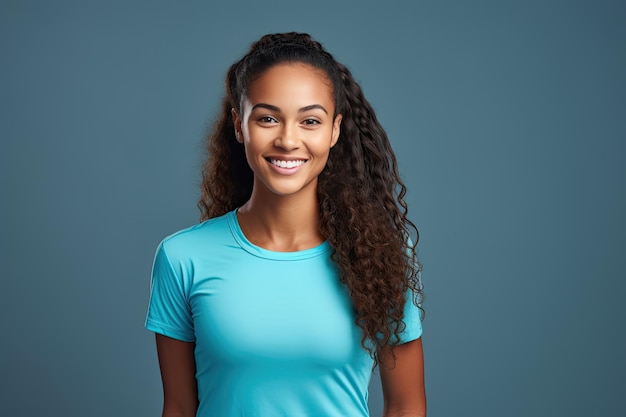 Portret van een gelukkig afro-meisje met lang golvend haar in sportkleding op een eenvoudige grijsblauwe achtergrond