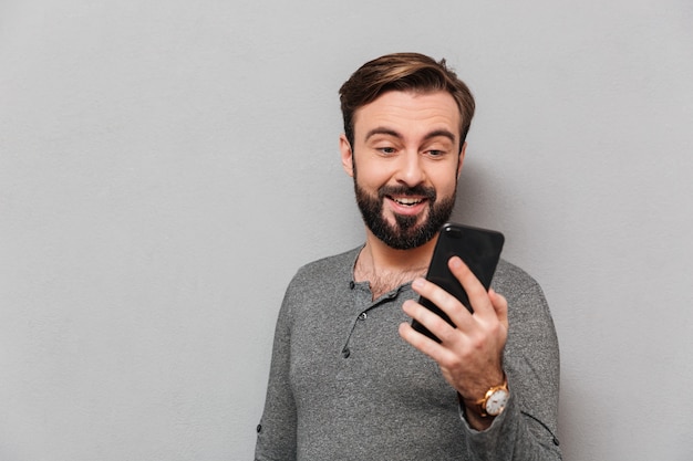 Portret van een gelukkig casual man kijken naar mobiele telefoon