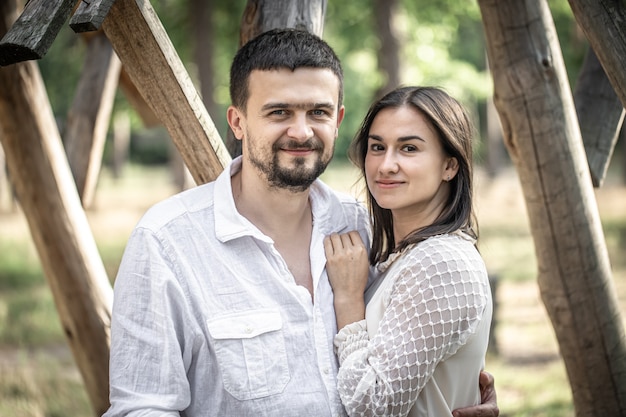 Portret van een gelukkig getrouwd stel, man en vrouw knuffelen op een onscherpe achtergrond in het bos.