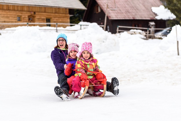 Portret van een gelukkig gezin dat op de sneeuw slee rijdt
