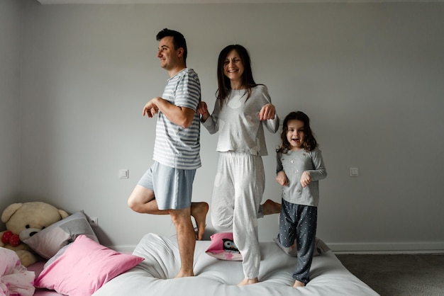 Portret van een gelukkig gezin in de ochtend, familie in pyjama, familiefoto, gelukkig jong gezin poseren in pyjama voor de camera, vader, moeder en dochter nemen een foto als aandenken