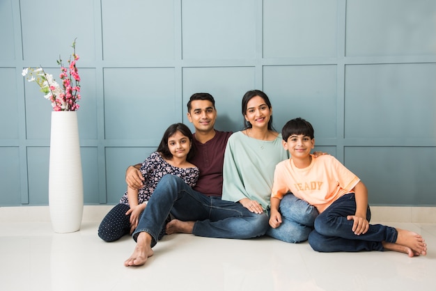 Portret van een gelukkig Indiaas Aziatisch jong gezin zittend op de bank, liggend op de vloer of zittend tegen de muur