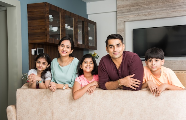 Portret van een gelukkig Indiaas Aziatisch jong gezin zittend op de bank, liggend op de vloer of zittend tegen de muur