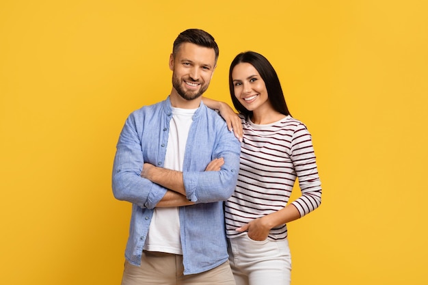 Portret van een gelukkig jong Europees echtpaar dat poseert op een gele achtergrond