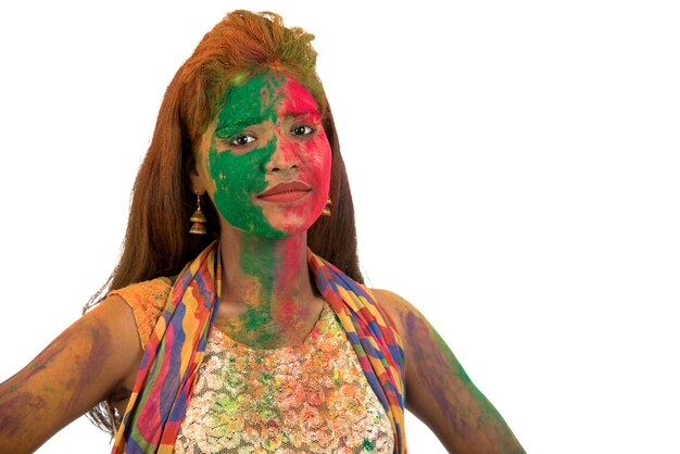 Portret van een gelukkig jong meisje met een kleurrijk gezicht op Holi-kleurenfestival op wit