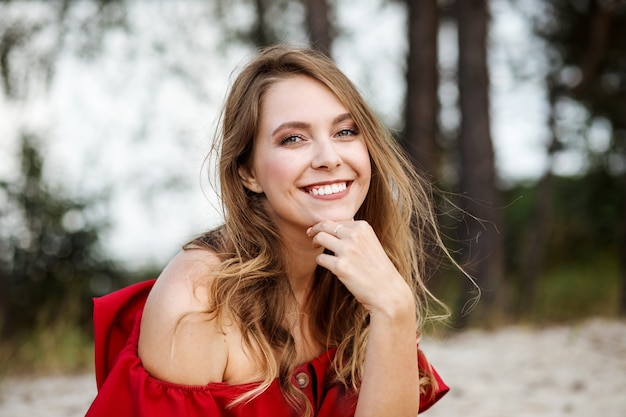 Portret van een gelukkig lachende blanke vrouw die in de zomer een rode jurk draagt