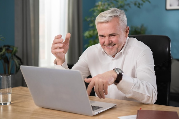 Portret van een gelukkig lachende man in zijn werk op een laptop in de woonkamer thuis een knappe g