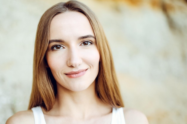 Portret van een gelukkig lachende vrouw die op een zomerdag naar de camera staat te kijken