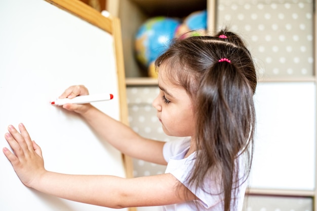 Portret van een gelukkig meisje dat tijdens de les met een stift op een modern smartboard schrijft