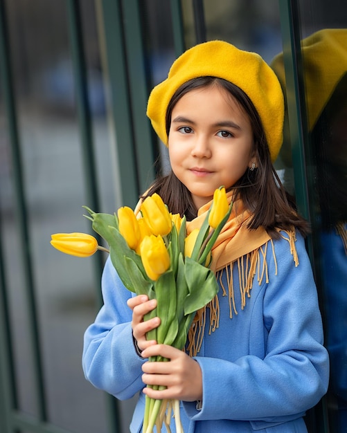 Portret van een gelukkig meisje met een boeket gele tulpen op een wandeling in de lente bloemen voor internationale vrouwendag