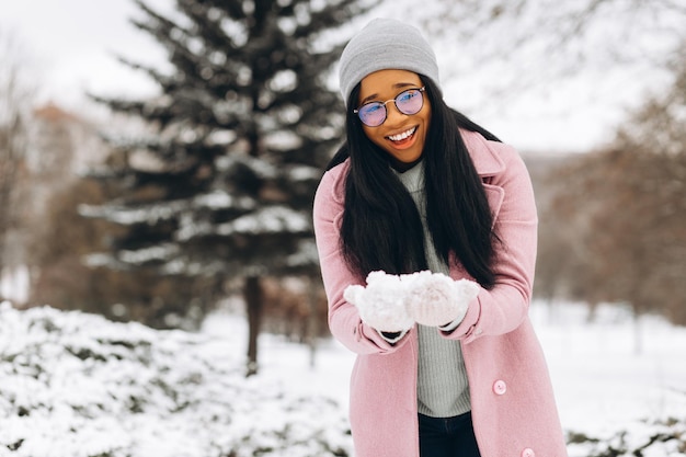 Portret van een gelukkig positief meisje afro-amerikaanse jonge vrouw in een bril en handschoenen in het winterpark