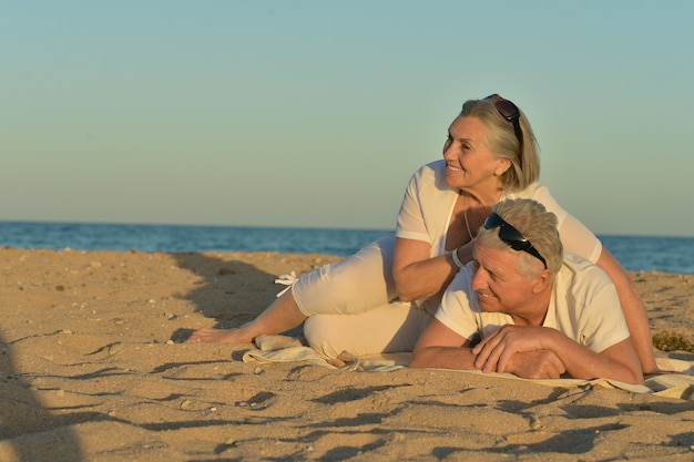 Portret van een gelukkig volwassen paar ontspannen op het strand