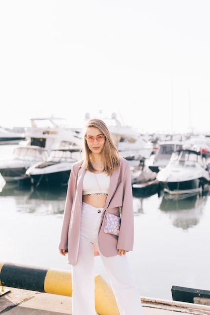 Portret van een gelukkig vrolijk emotioneel reizend meisje in modieuze kleren bij jachten en water