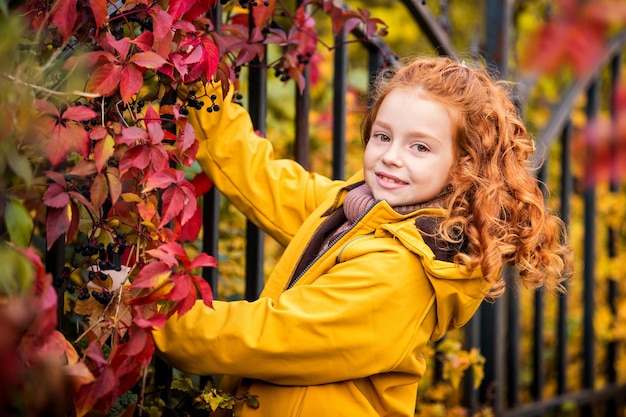 Portret van een gelukkig vrolijk roodharig krullend tienermeisje in de natuur tussen het heldere herfstbos