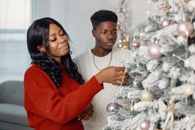 Portret van een gelukkig zwart paar dat de kerstboom versiert