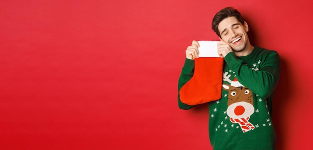 Portret van een gelukkige aantrekkelijke man in een groene trui die op zoek is naar geschenken in de kerstst...