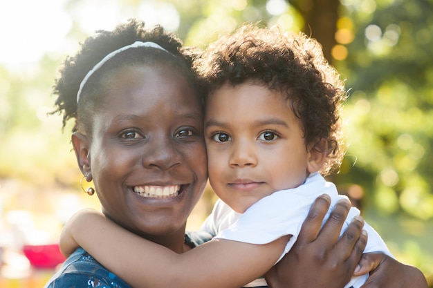 Portret van een gelukkige Afrikaanse moeder en baby die de camera omhelzen en bekijken.