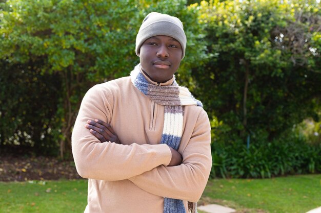 Foto portret van een gelukkige afro-amerikaanse man die in de tuin staat met een wollige muts en sjaal. huiselijk leven, vrije tijd en positiviteit, tijd alleen thuis doorbrengen.