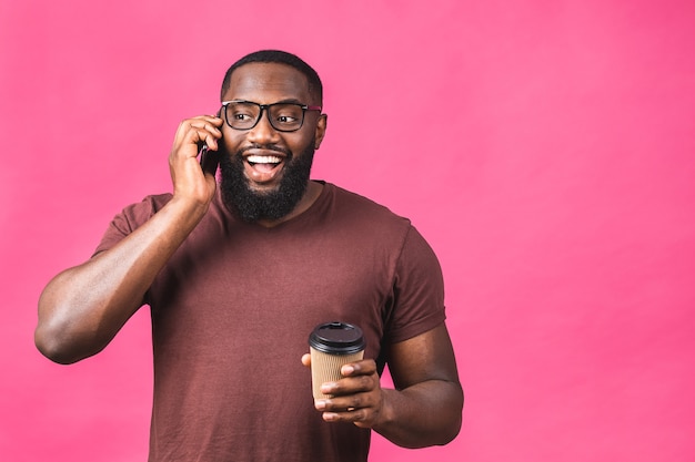 Portret van een gelukkige afro-amerikaanse man praten op mobiele telefoon geïsoleerd tegen roze achtergrond.