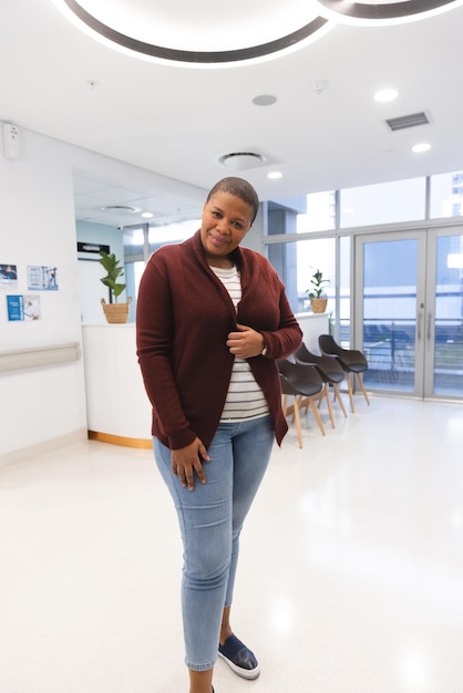 Portret van een gelukkige Afro-Amerikaanse vrouwelijke patiënt in de wachtkamer van een ziekenhuis. Ziekenhuis, medicijnen en gezondheidszorg, onveranderd.