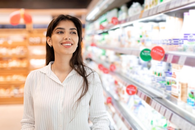 Portret van een gelukkige Arabische vrouwelijke klant die in de supermarkt staat