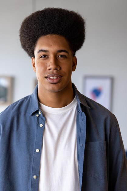 Portret van een gelukkige bi-raciale casual zakenman met afro glimlachend op kantoor. Casual kantoor, zaken en werk, ongewijzigd.